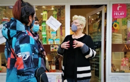 Dues voluntàries de la Plataforma per la Llengua conversen amb una comerciant